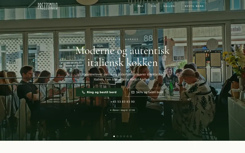 Startseite von prezzemolo.dk: Gäste an den Tischen der kleinen Osteria, durch die großen Fenster gesehen, mit der dänischen Überschrift „Moderne og autentisk italiensk køkken“.